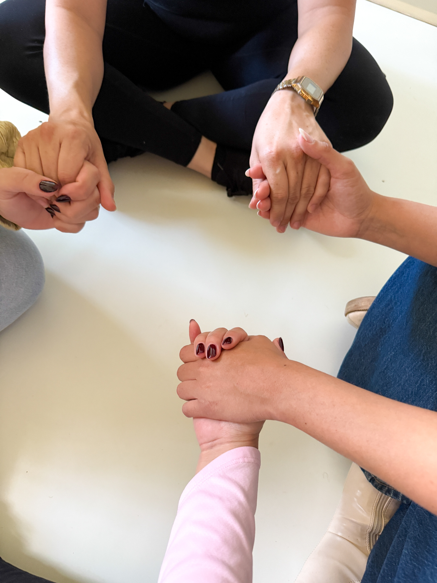 Women holding hands in prayer at a Fellowship gathering